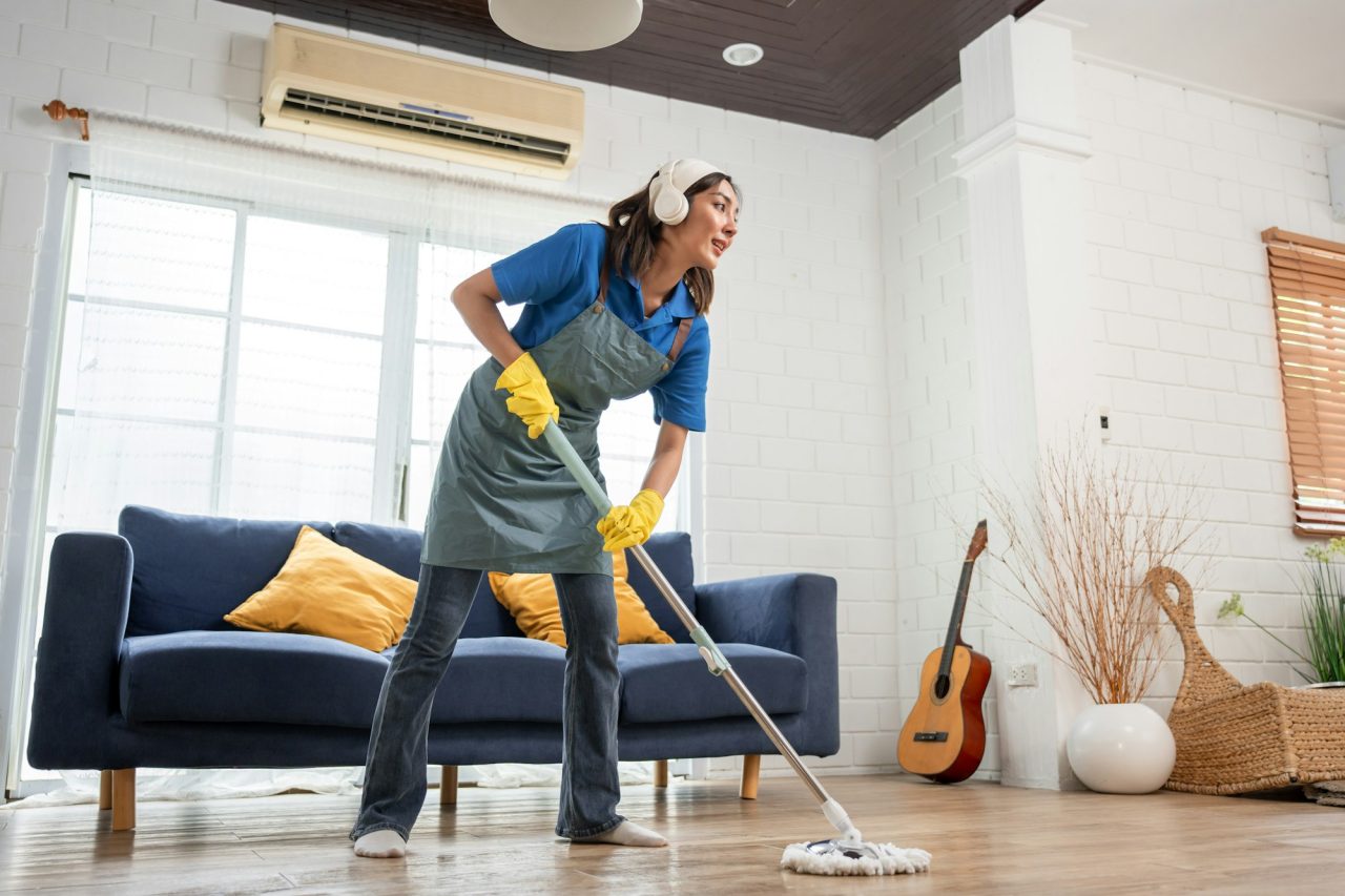 Asian beautiful woman cleaner cleaning indoors in living room at home.